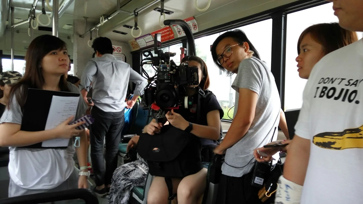 Camera crew and cast filming inside the moving bus.